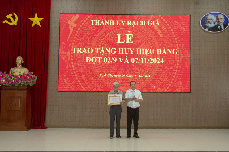 Đồng chí Nguyễn Thanh Phong - Ủy viên Ban Thường vụ Tỉnh ủy, Bí thư Thành ủy Rạch Giá trao huy hiệu 75 năm tuổi Đảng cho đảng viên Trần Kiều sinh hoạt tại Đảng bộ phường Vĩnh Lợi